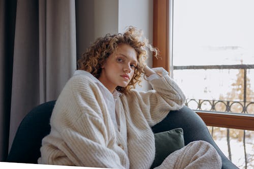 A Woman In Knitted Sweater Sitting on a Chair