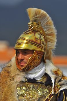 Portrait of a Roman soldier in ornate golden armor and helmet.