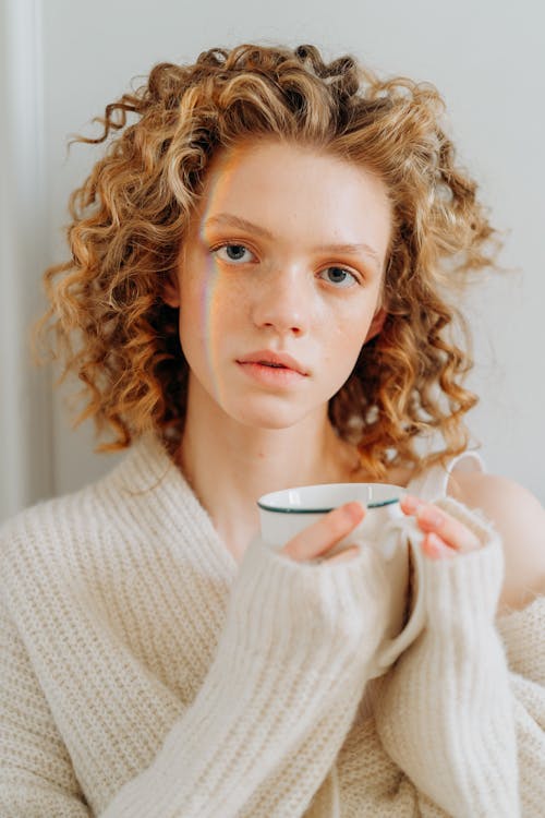 Woman in White Knit Sweater Holding White Ceramic Mug