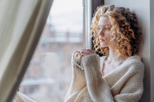 A Woman Wearing a Knitted Sweater and Holding a Cup