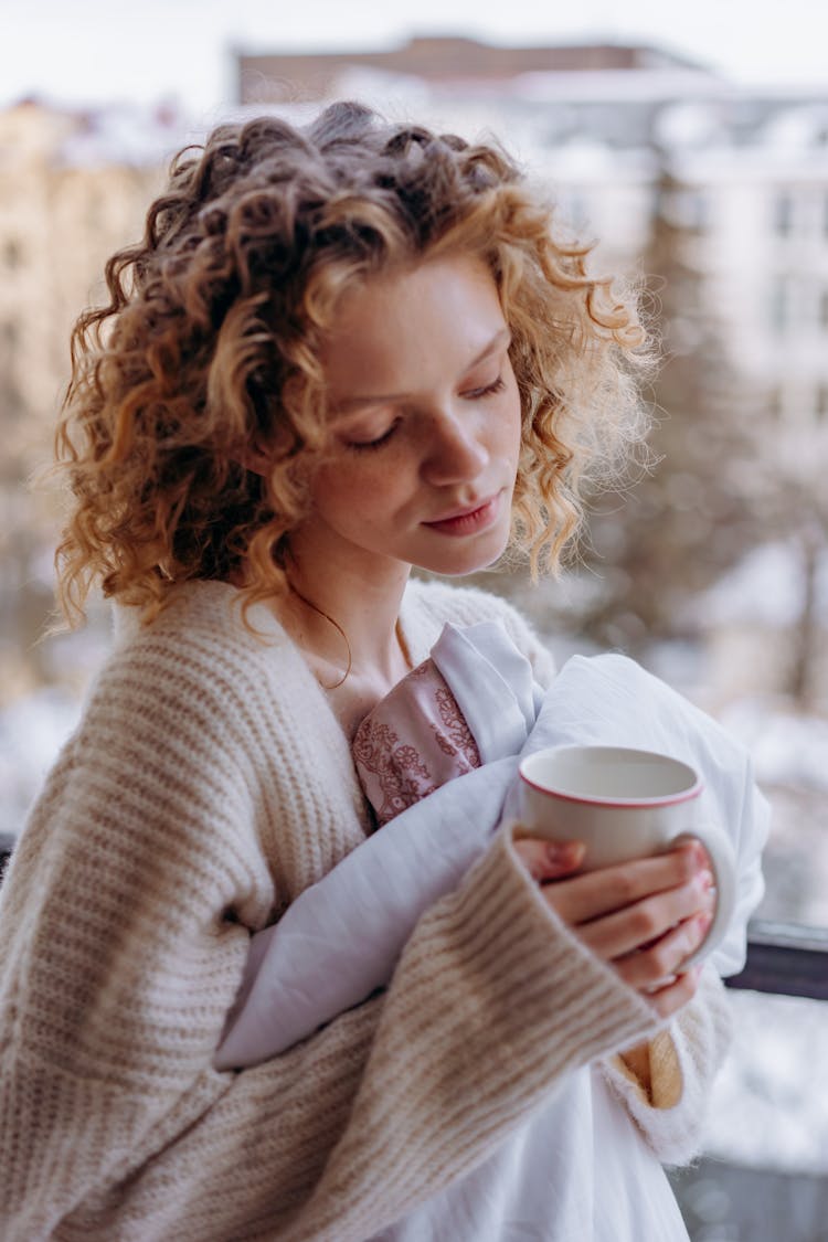 Woman In White Knit Sweater Holding White Ceramic Mug Looking Down