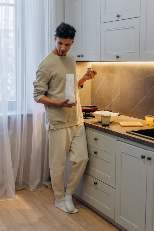 Man in Beige Long Sleeve Shirt and Pants Standing beside Kitchen Counter