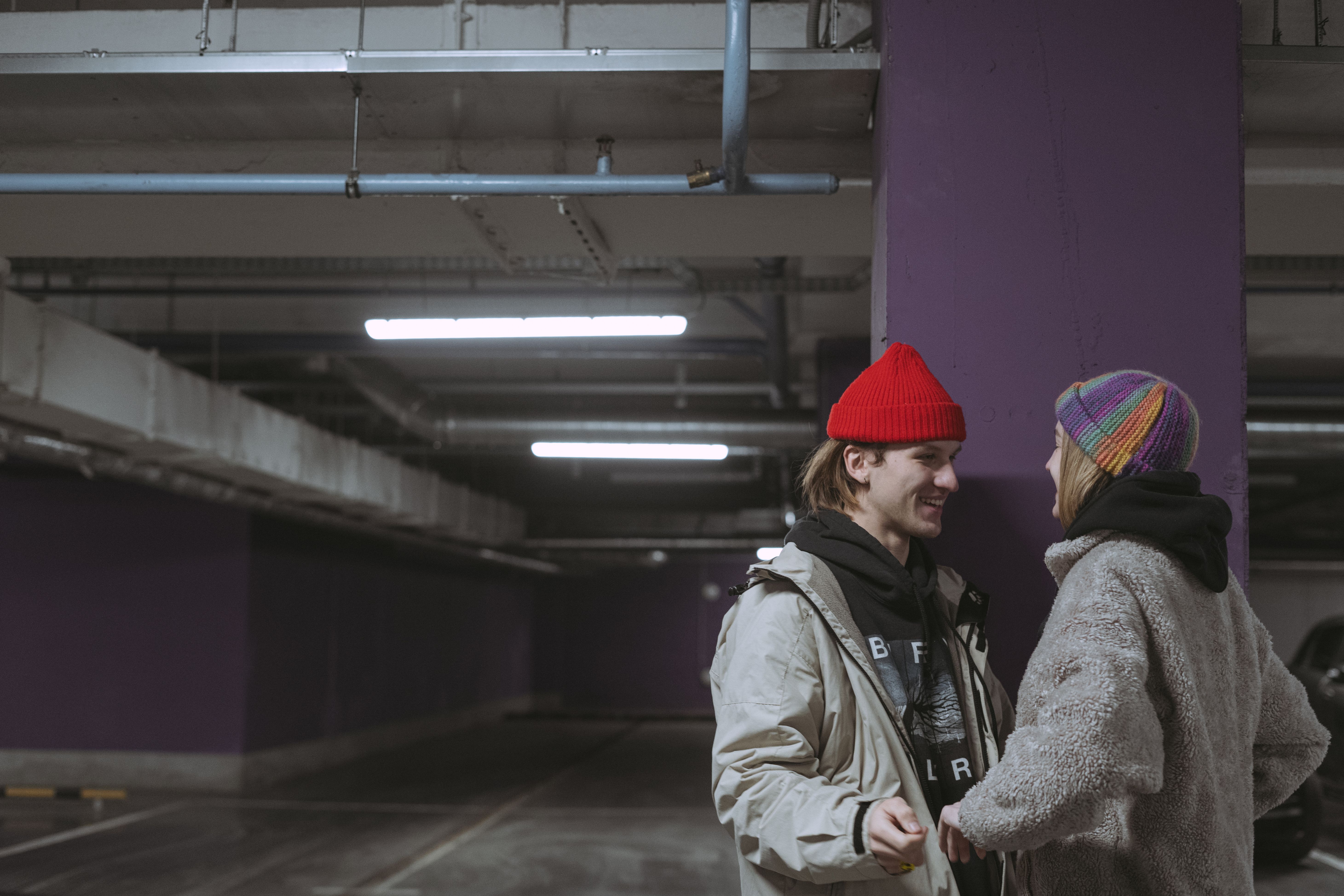 Couple en bonnets streetwear dans un parking urbain, accessoires mode urbaine en situation