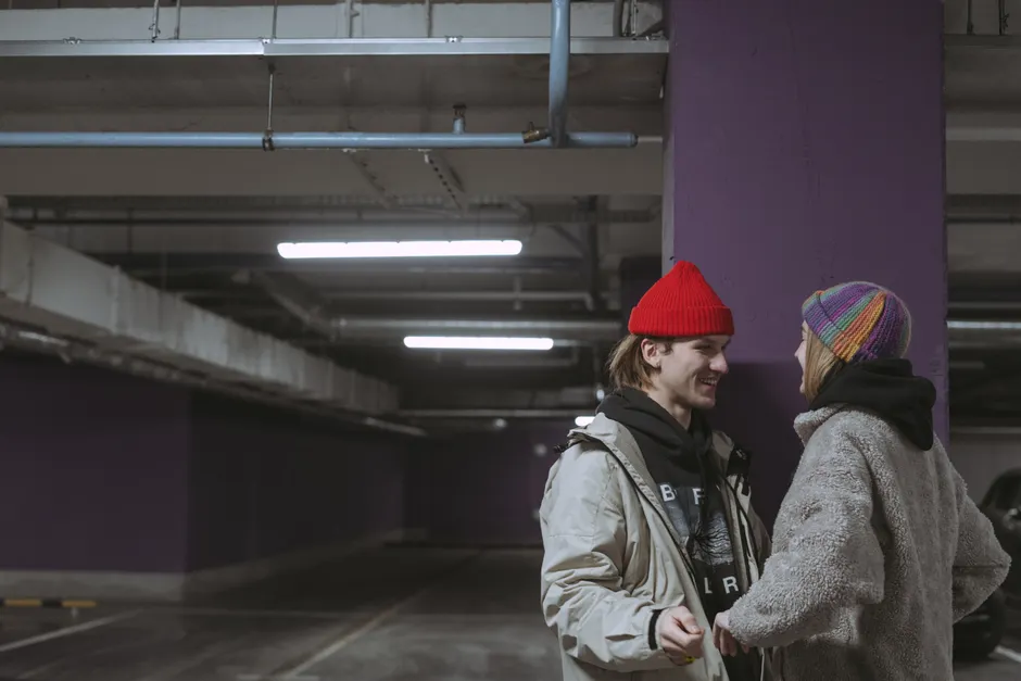 Couple en bonnets streetwear dans un parking urbain, accessoires mode urbaine en situation