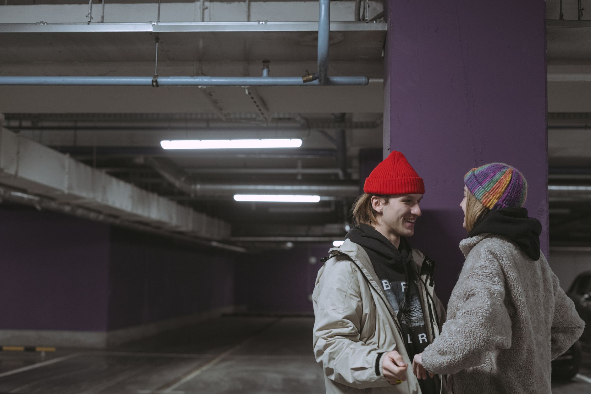 Couple en bonnets streetwear dans un parking urbain, accessoires mode urbaine en situation