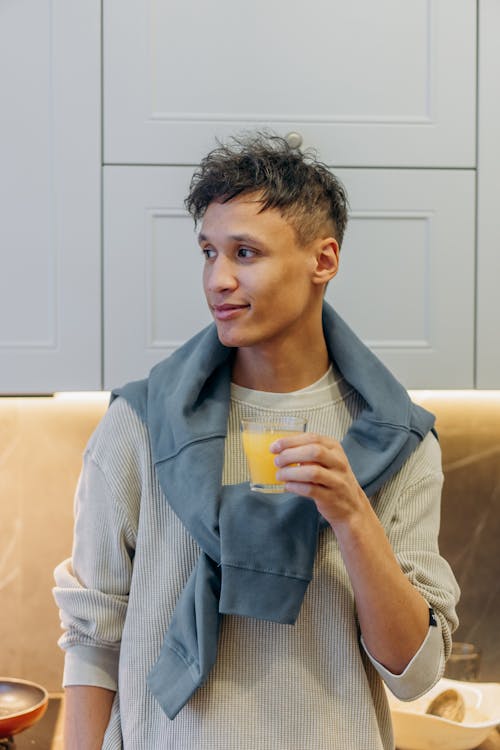 A Man Holding a Glass of Juice while Looking Afar