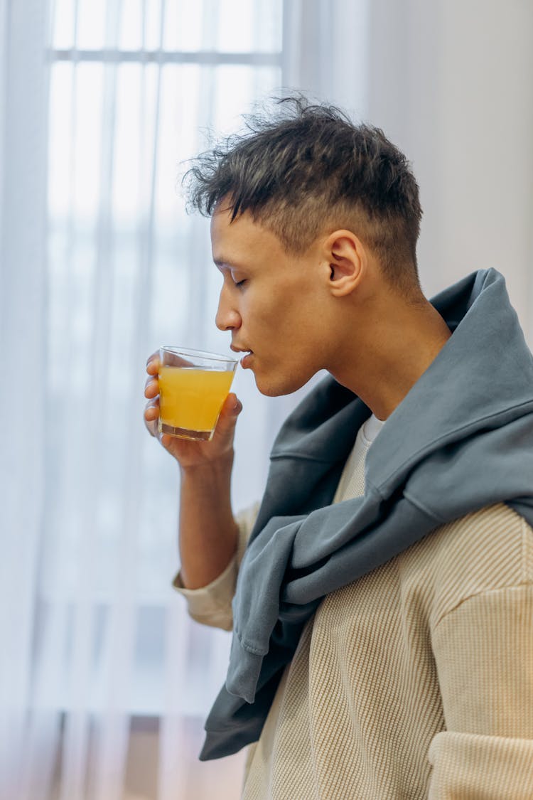 
A Man Drinking A Glass Of Juice