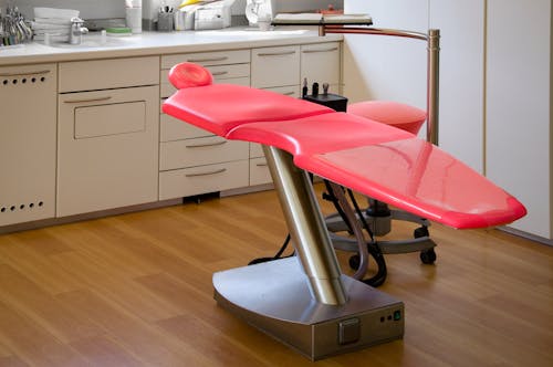 灰色の金属フレームの赤い歯科治療椅子