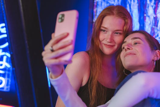 Two young women happily taking a selfie with a mobile phone indoors.
