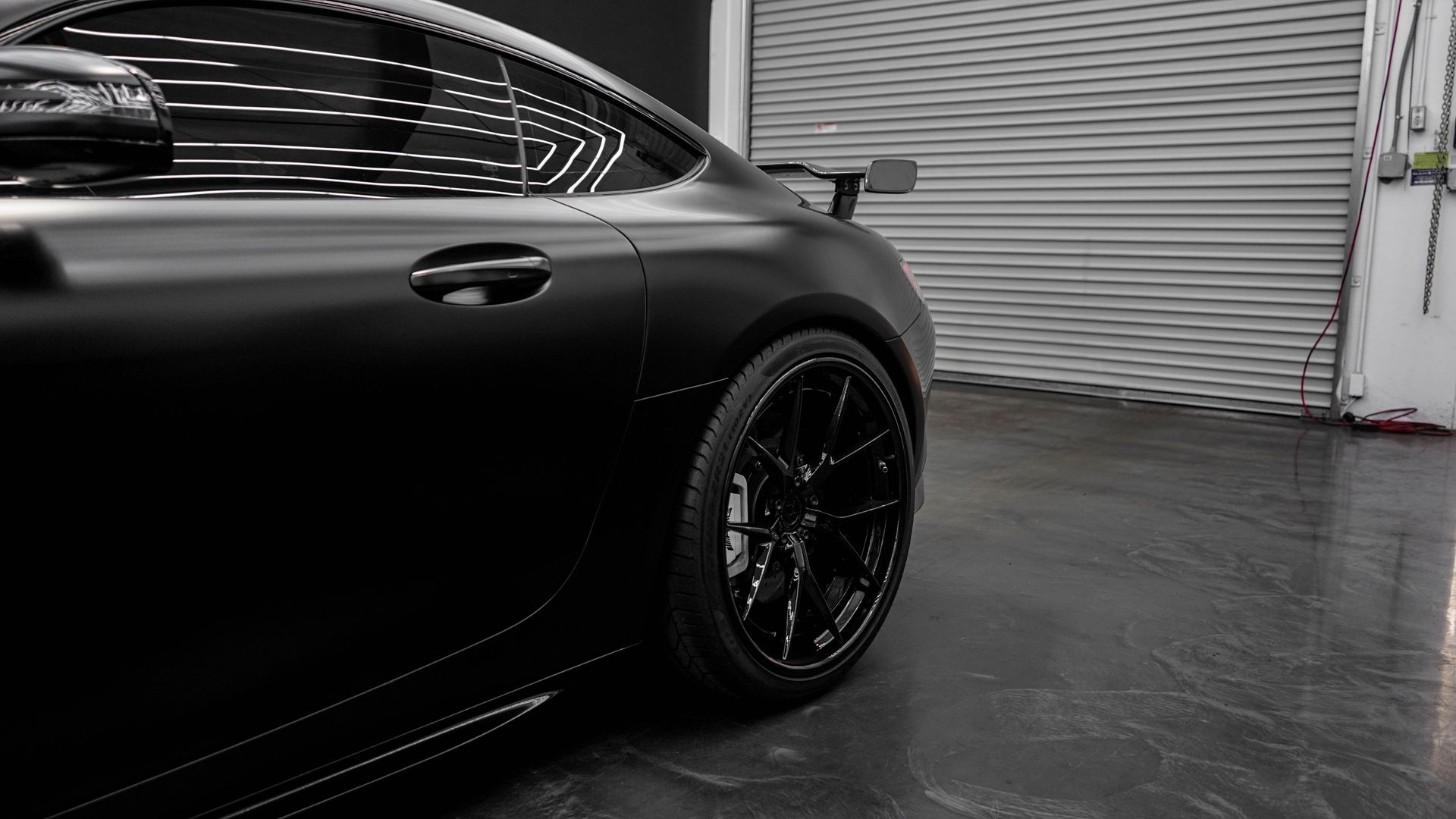 Sleek black car with matte finish parked in a modern garage, showcasing luxury and style.