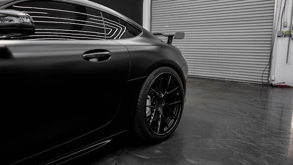 Auto sportiva con carrozzeria nero opaco parcheggiata davanti a un garage