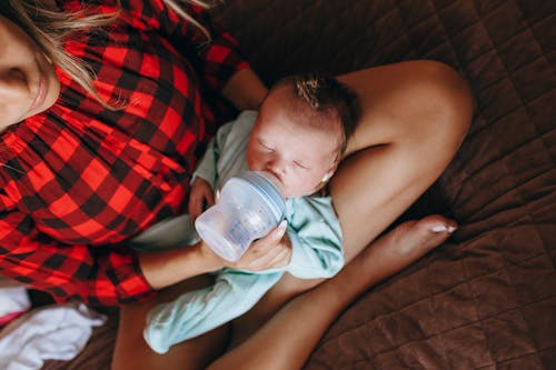 Faceless mother feeding newborn baby