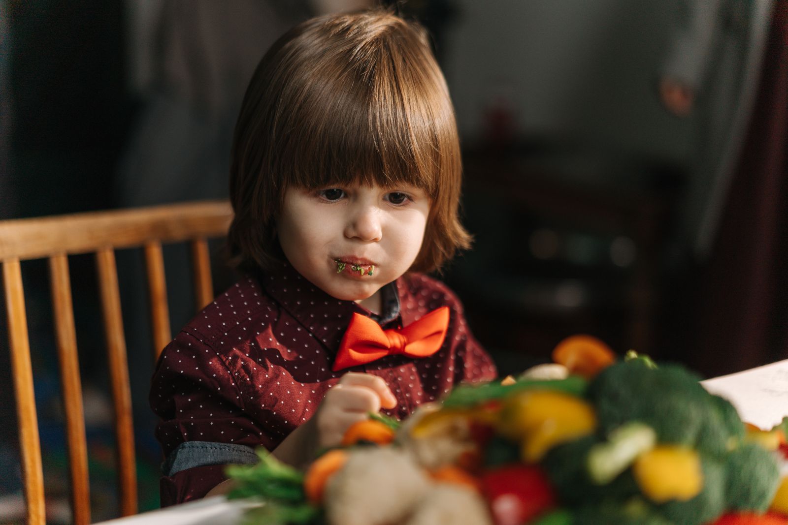 Bambino seduto a tavola davanti a un piatto di verdure