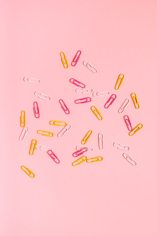 Free Bright and playful arrangement of paper clips on a pink backdrop. Stock Photo