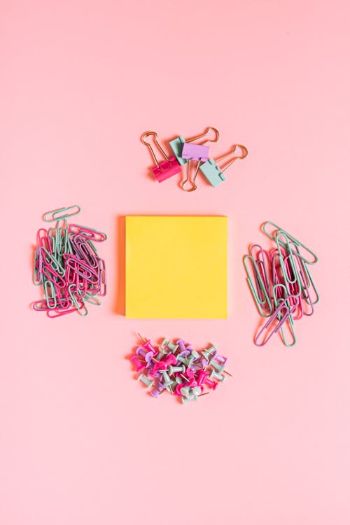 Yellow Post It and Paper Clips on Pink Background