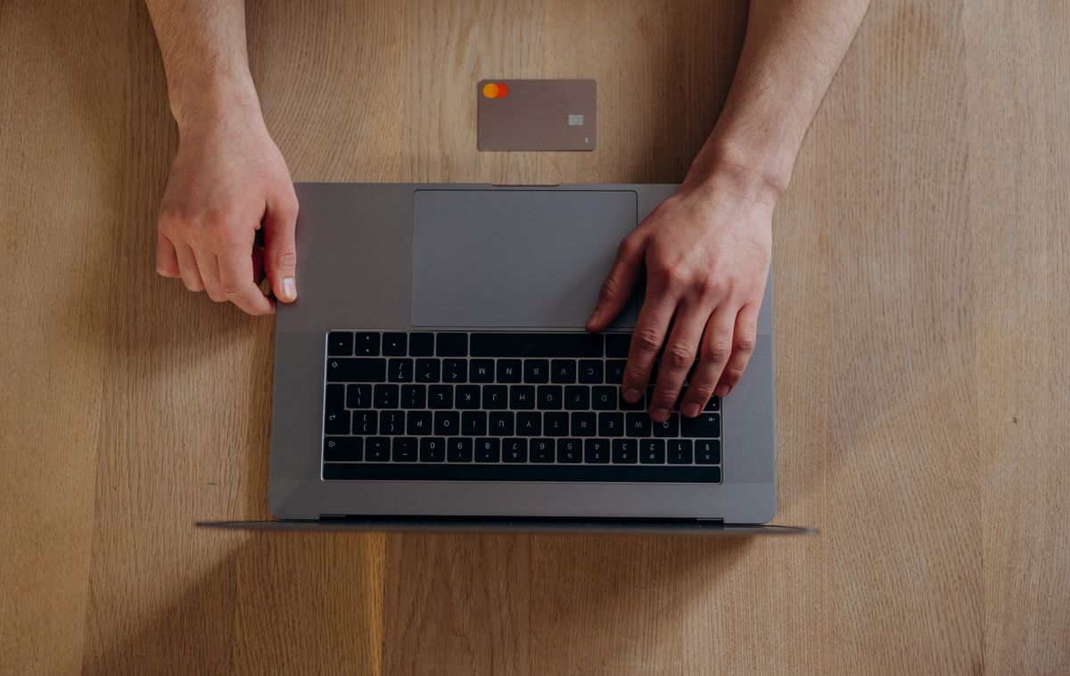 Kredi kartı ve dizüstü bilgisayar ile online ödeme işlemi yapan kişi