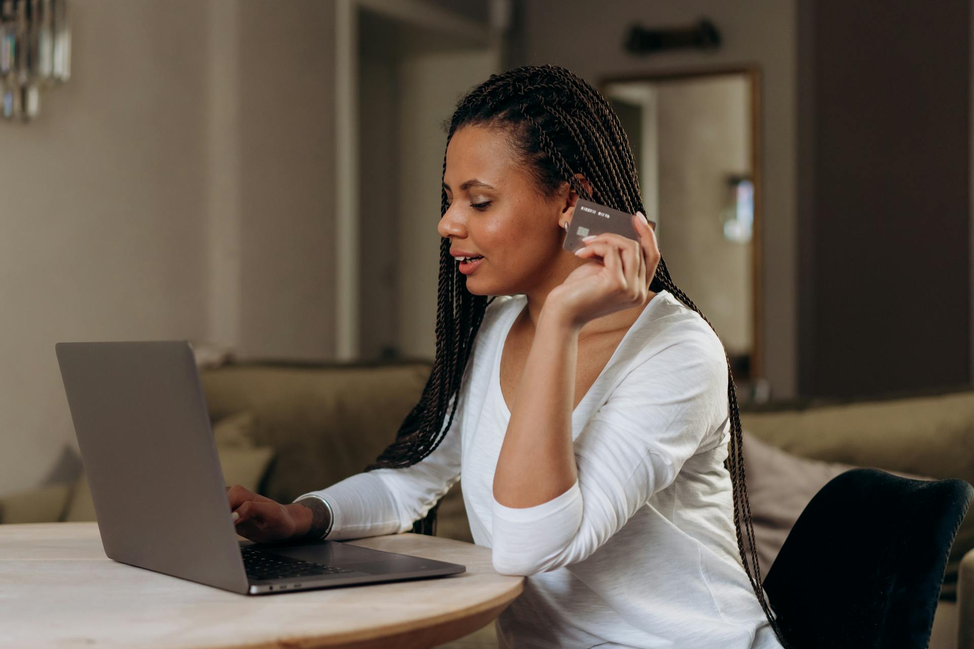 Woman shopping online at home using a laptop and credit card. Convenient cashless transaction concept.