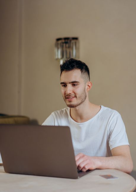 Smiling young adult using a laptop for online shopping indoors. Modern digital lifestyle. Smiling young adult using a laptop for online shopping indoors. Modern digital lifestyle.