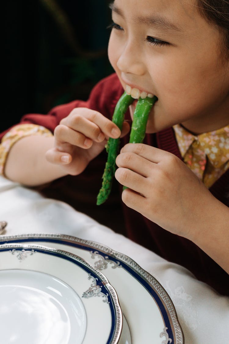 Close-Up Shot Of A Child Eating Asparagus