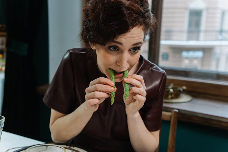 Close-Up Shot Of A Woman Eating Asparagus