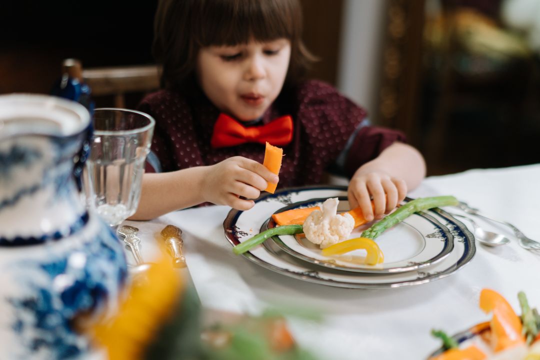 Child Nutrition Guide: What to Feed Kids (Chef-Approved) 1 A toddler enjoying a healthy vegetarian meal with fresh colourful vegetables including bell peppers and carrots.