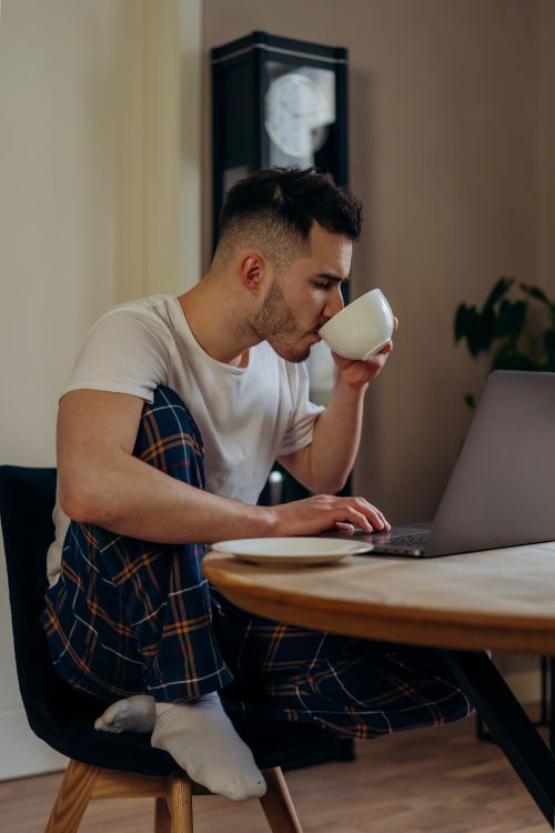 Free Casual work from home setup with a laptop and cup of coffee, morning productivity. Stock Photo