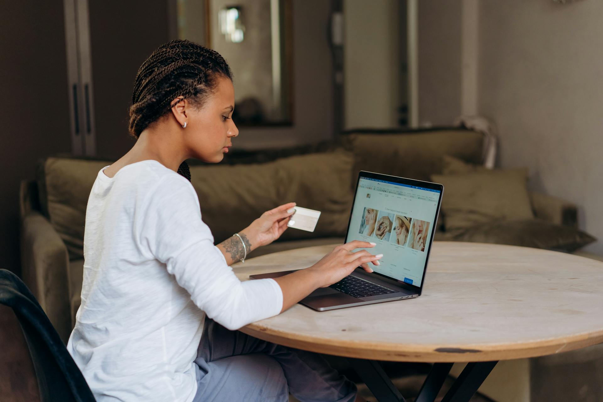 African American woman uses a credit card for an online purchase on her laptop at home.