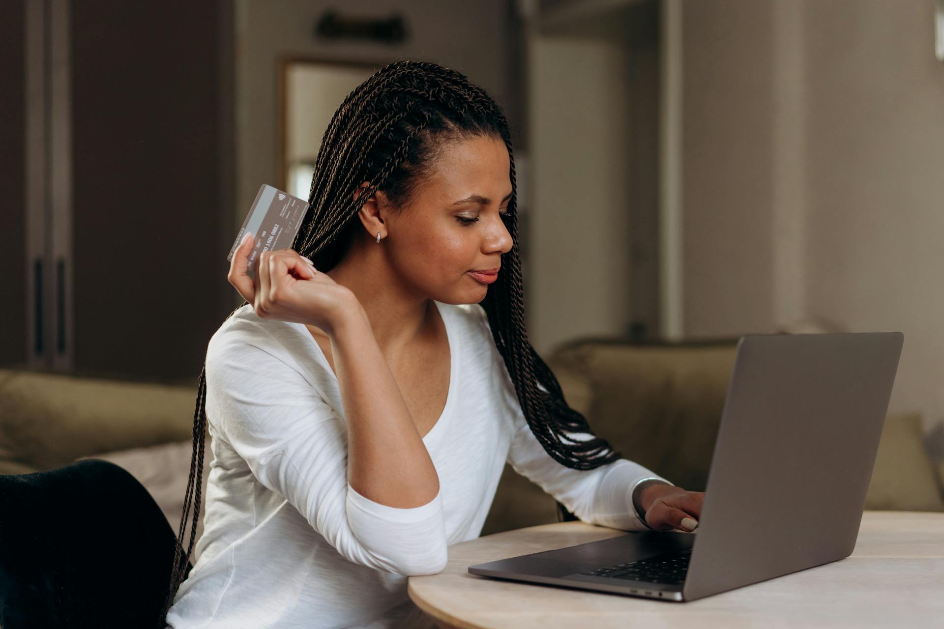 Confident woman using a laptop and credit card for online shopping at home.