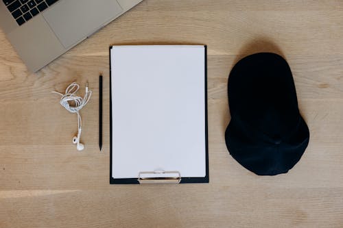 A Clipboard and Earphones on a Wooden Surface