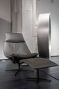 Creative interior of room with modern leather chair and footrest in flat with minimalistic design