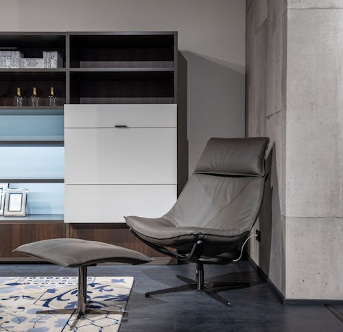 Chair with footrest near cupboard in stylish apartment