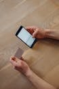 A Person Holding Black Smartphone and White Credit Card