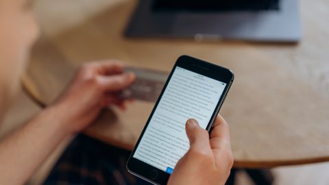 Close-up of a person holding a smartphone and credit card. Ideal for online shopping concepts.