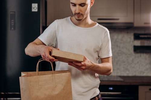 Free Man in White Crew Neck T-shirt Holding Brown Paper Box Stock Photo