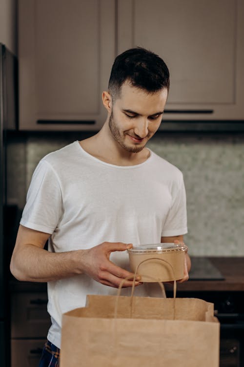 Man in White Shirt Holding Brown Food Container