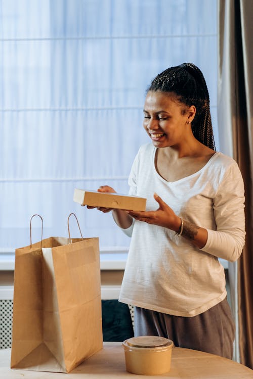 Woman in White Long Sleeve Shirt Holding Brown Box