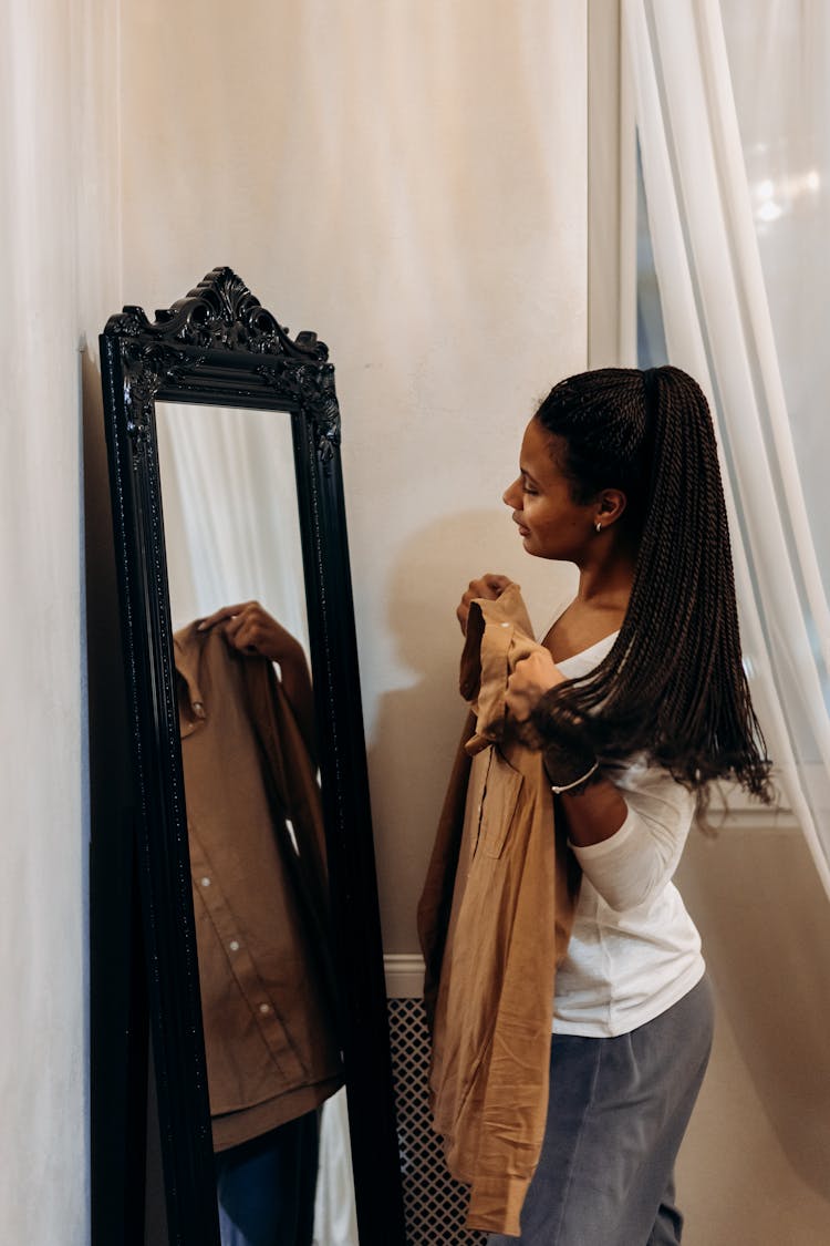 A Woman Fitting A Brown Long Sleeves Shirt Looking Through A Mirror