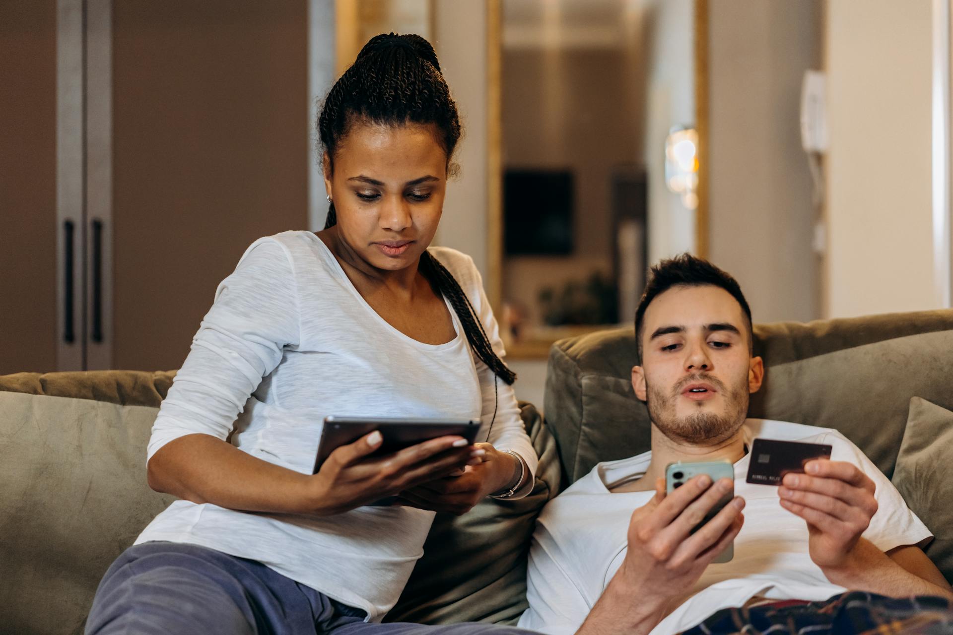 A couple uses a smartphone and tablet for online shopping at home.