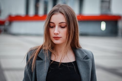 Free Stylish portrait of a woman in Kyiv featuring a gray coat against an urban backdrop. Stock Photo