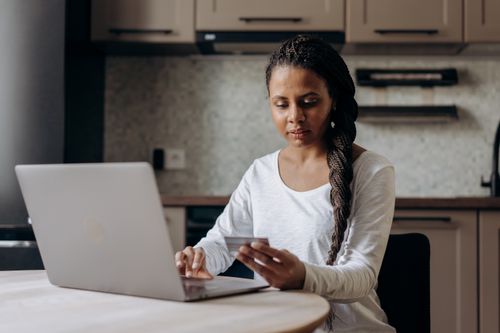 Free African American woman using laptop and credit card for online shopping at home. Stock Photo