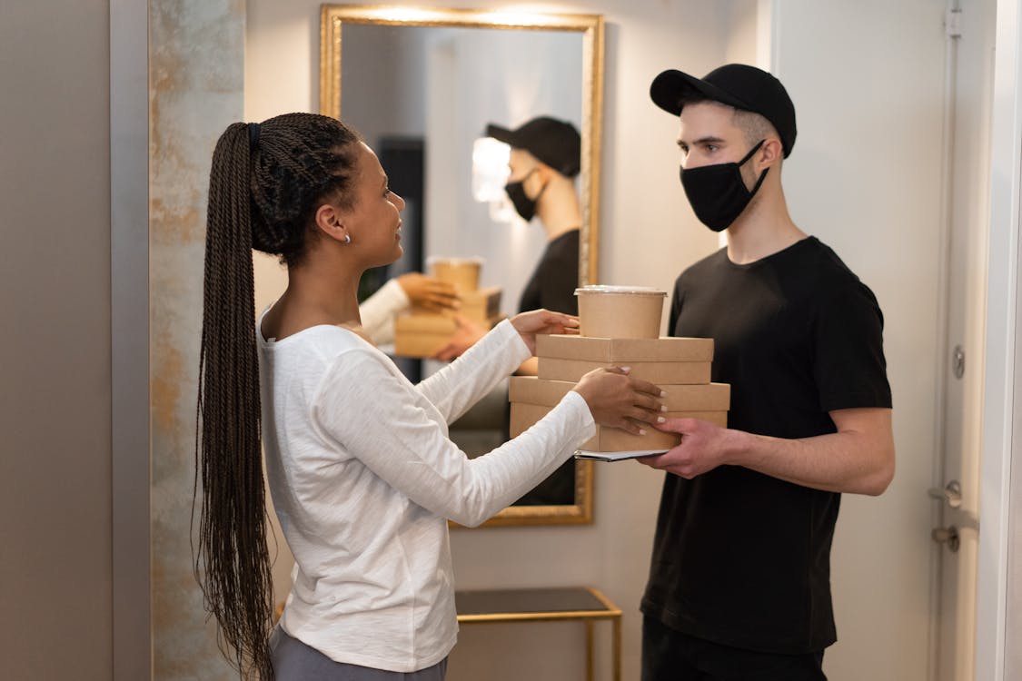 Free Man in Black Shirt and Black Face Mask Holding Brown Boxes Stock Photo
