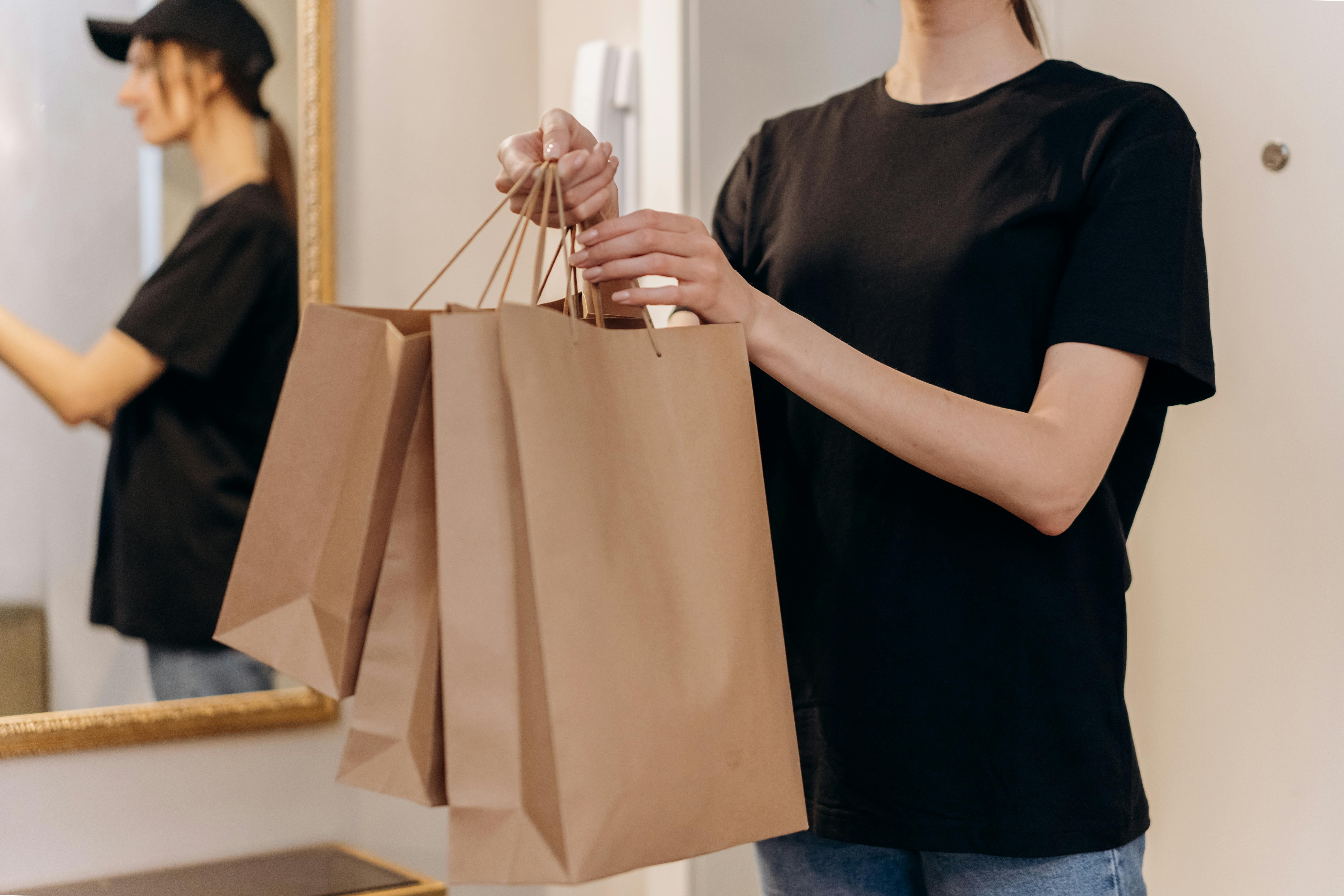 Woman in black shirt holding paper bags indoors, perfect for shopping concepts.