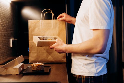 Man in a White Shirt Holding a Box with Food