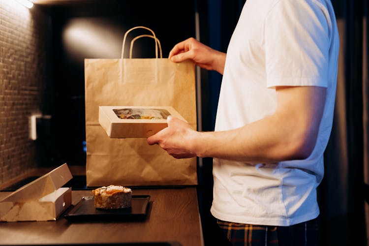 Man In A White Shirt Holding A Box With Food