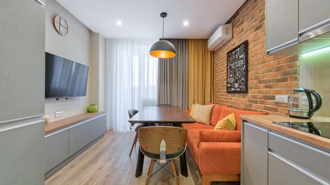 Stylish apartment interior with a brick wall, orange sofa, and wooden furniture.