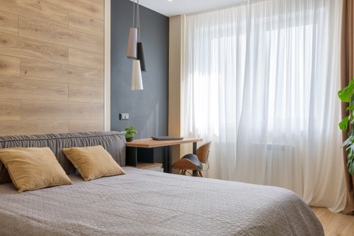 Free Bright and airy bedroom featuring modern design elements, wooden accents, and natural lighting. Stock Photo