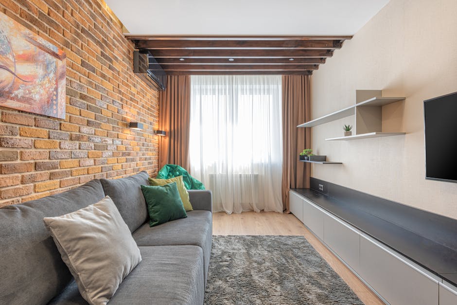 Nowoczesny salon z meblościanką i szarym tapczanem naprzeciw, szerokie przejście i ukryte kable