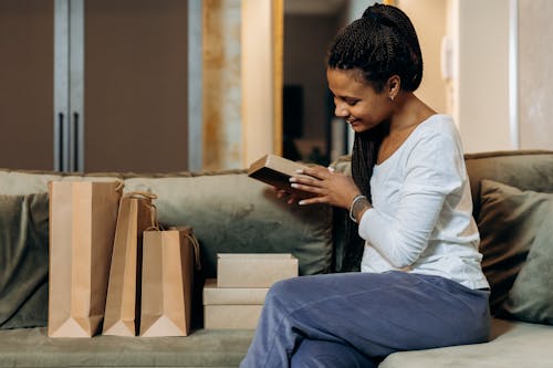 Free Woman Sitting on Couch with Brown Paper Bags and Boxes Stock Photo