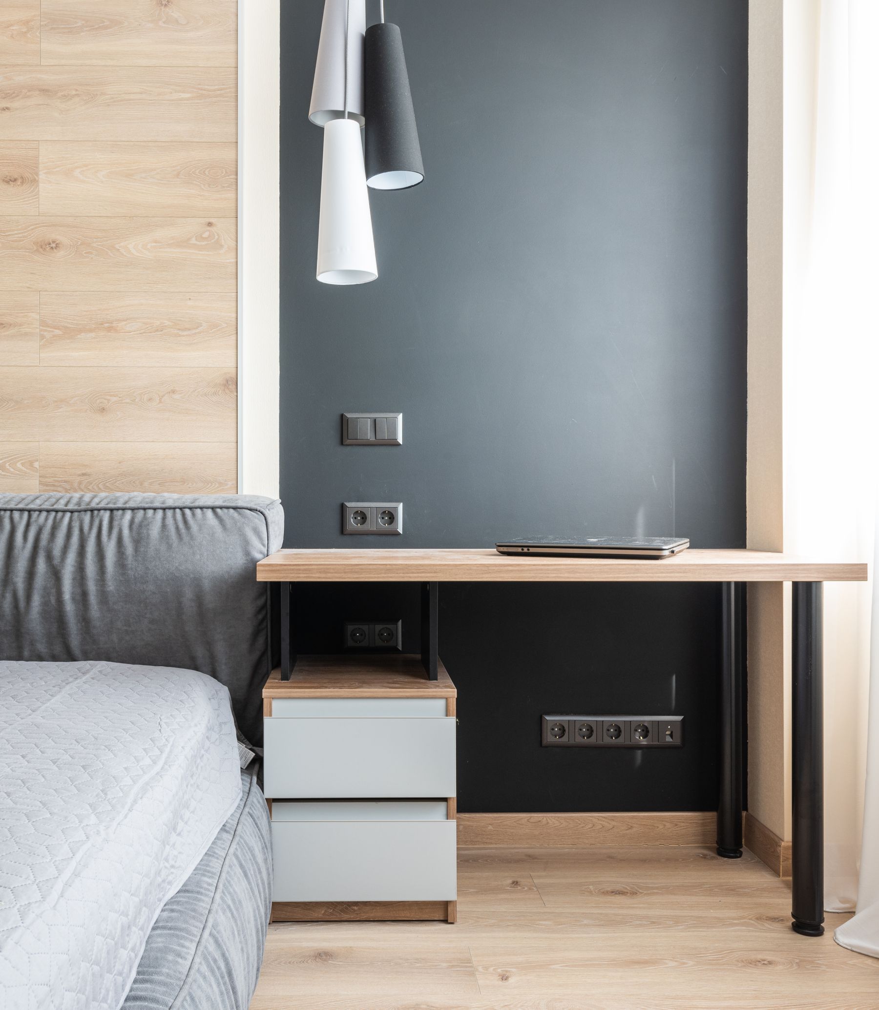 Black bedroom wall beside a warm wooden desk with clean linear detailing