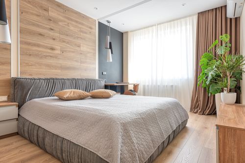 Free A clean and bright modern bedroom featuring wooden accents, neutral tones, and a potted plant. Stock Photo
